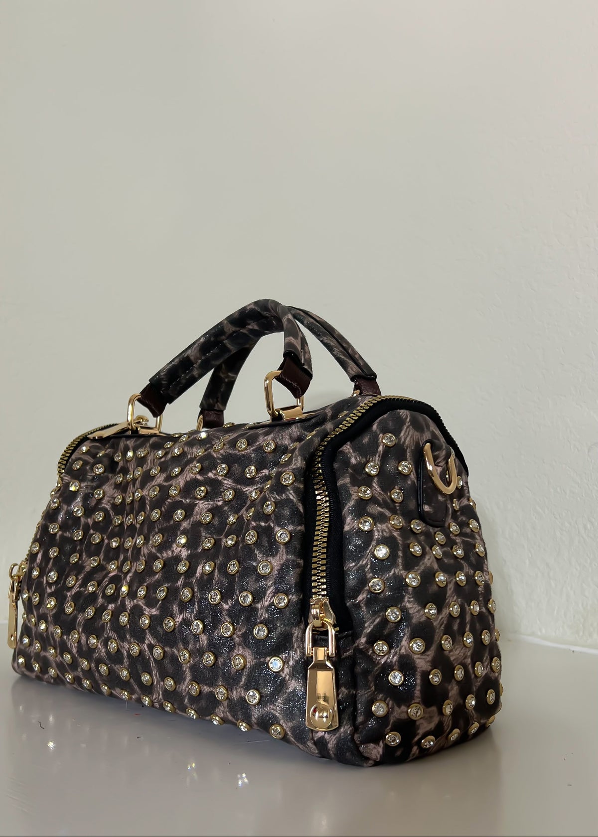 Leopard print handbag with gold accents on a white background